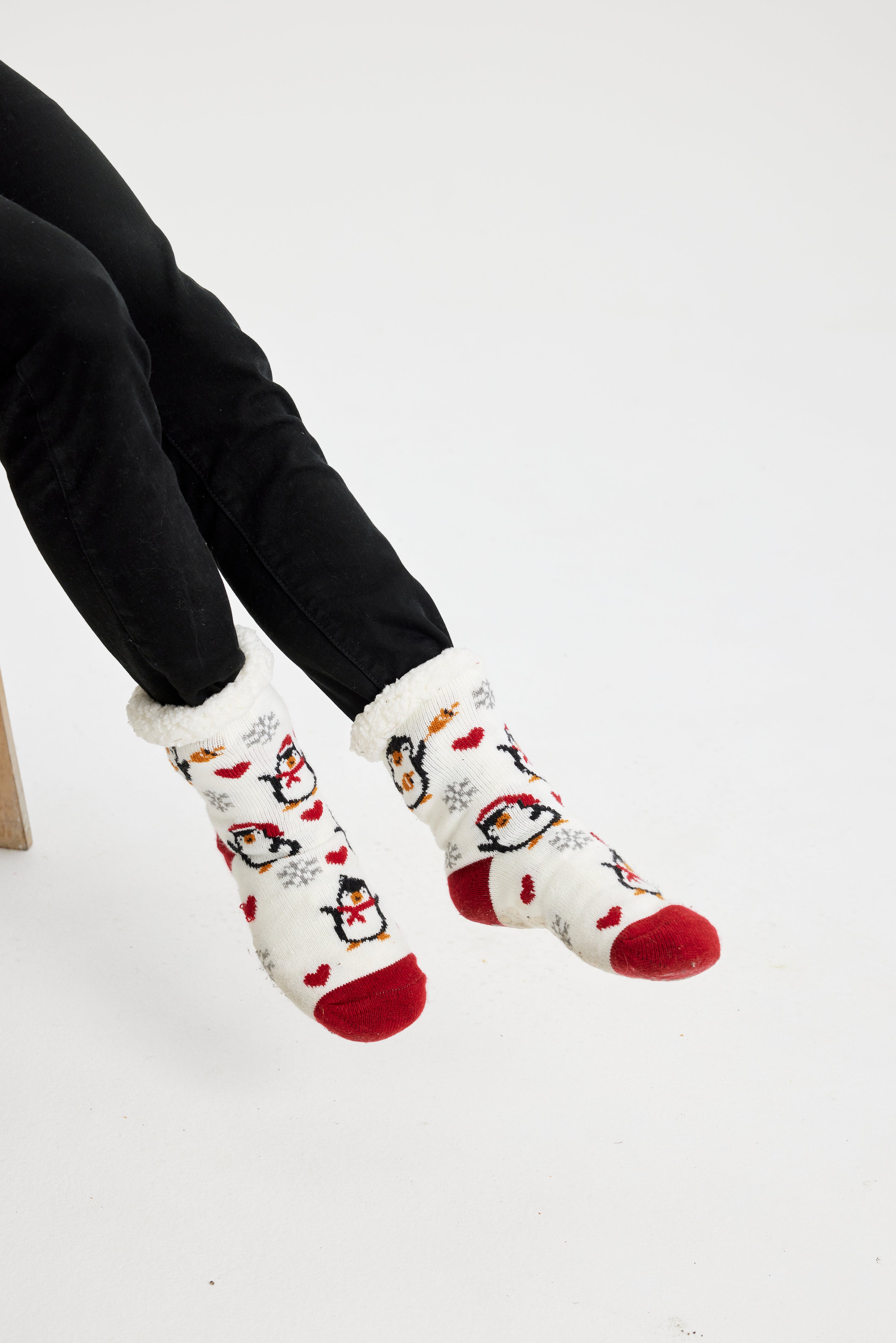 Et par føtter med hvite julesokker med pingviner på.